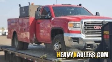 Loading a GMC Sierra service truck on a trailer.